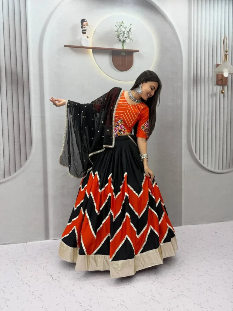 Model in a black and orange chevron lehenga with an orange choli and black dupatta